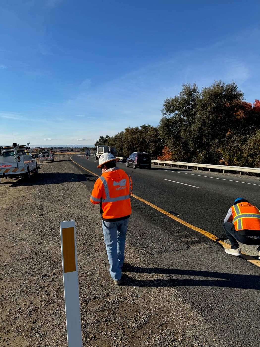 Crew members in high-visibility gear working along an active highway shoulder