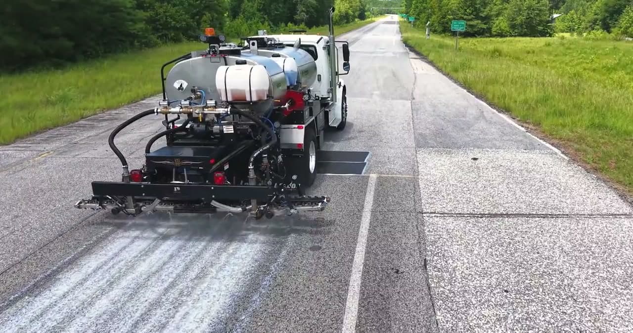 LeeBoy PR900 distributor seen from behind, applying a treatment along a paved test lane